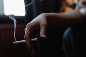 Hand met brandende sigaret, symbool voor roken en de invloed op de overlijdensrisicoverzekering